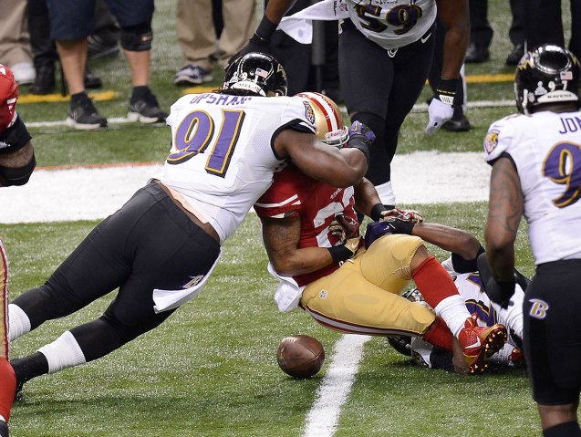 LaMichael James of the San Francisco 49ers fumbles as he is hit by Courtney Upshaw of the Baltimore Ravens in the first half of Super Bowl XLVII at the Mercedes-Benz Superdome in New Orleans, Feb. 3, 2013.