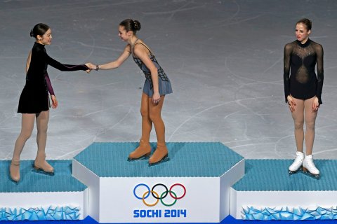 First-placed Russia's Adelina Sotnikova (C) shakes hands with second-placed South Korea's Kim Yuna (L) as third-placed Italy's Carolina Kostner looks on, on the podium after the figure skating women's free skating program.