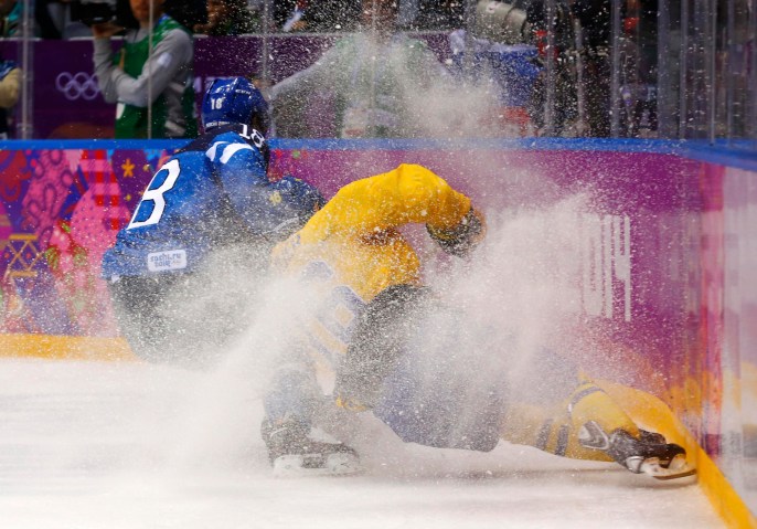 Finland's Lepisto and Sweden's Kruger head into the corner during the second period of their men's play-off semi-final ice hockey game at the Sochi 2014 Winter Olympic Games