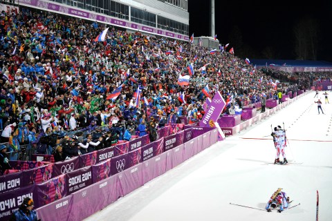Gold medalist Martin Fourcade and bronze medalist Jean Guillaume Beatrix, both of France, celebrate while silver medalist Ondrej Moravec of the Czech Republic lies on the ground in the finish area of the Biathlon Men's 12.5km Pursuit at the Laura Cross-country Ski & Biathlon Center.