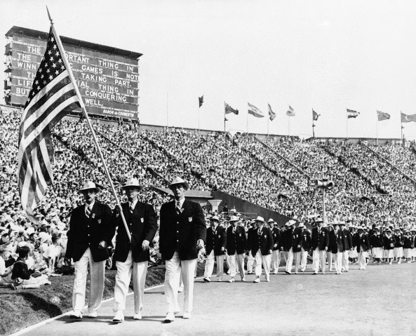 Ralph Craig, center, of Albany, N.Y., carries the American flag in the parade of the nations at the opening of the summer Olympic games in London's Wembley Stadium, July 29, 1948.  