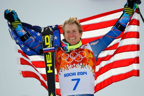 Winner Ted Ligety of the U.S. holds up his national flag during the flower ceremony for the men's alpine skiing giant slalom event in the Sochi 2014 Winter Olympics at the Rosa Khutor Alpine Center